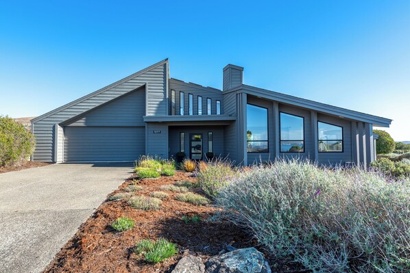 A modern coastal home with large windows offering sweeping views