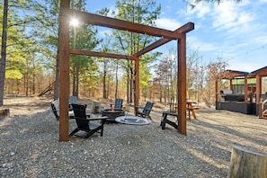 A cozy firepit area complete with Adirondack chairs, a saucer swing, and a bench swing—perfect for everyone to gather, relax, and create unforgettable memories around the fire.