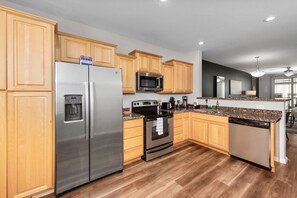 Modern functional kitchen with microwave, fridge, stove and basic cooking ware
