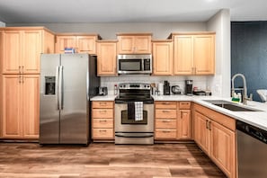 Modern functional kitchen with microwave, fridge, stove and basic cooking ware