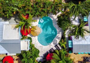 This tropical oasis, surrounded by lush greenery and colorful umbrellas, offers a stunning escape with its sparkling pool and serene lounge areas, perfect for soaking up the sun.