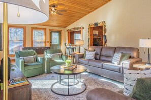 Sunlit living room with vaulted ceilings, plush seating, and nature views.
