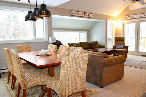 Stylish and comfortable living room and dining area, decorated in wooden tones, with breathtaking views of the Killington landscape.