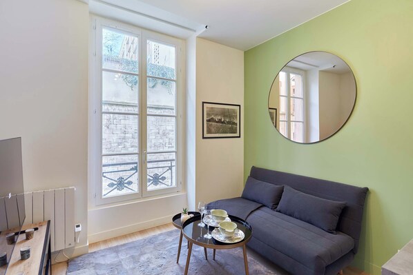 Pièce principale avec canapé lit, TV et cuisine