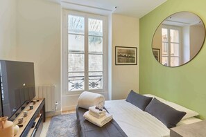 Pièce principale avec canapé lit, TV et cuisine
