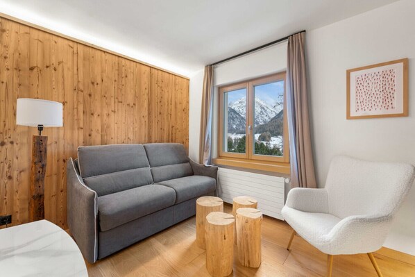 Living room with panoramic view, luxury Alpine design, and refined wooden furnishings.