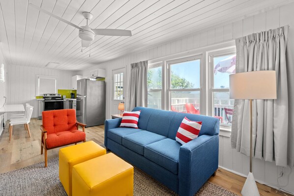 Bright and inviting living space featuring a modern design with vibrant pops of color. Relax on the cozy blue sofa, enjoy the spacious layout, and watch your favorite shows on a sleek wall-mounted TV. Perfect for unwinding after a day of adventure.