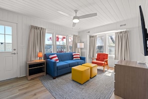 Bright and inviting living space featuring a modern design with vibrant pops of color. Relax on the cozy blue sofa, enjoy the spacious layout, and watch your favorite shows on a sleek wall-mounted TV. Perfect for unwinding after a day of adventure.