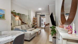 Spacious and inviting living room with a TV, dining table, and chic mirrors.