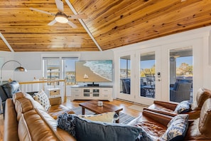 Spacious living area with a recliner, a comfortable sofa and 2 chairs along with 70 inch flat screen TV.