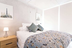 Relax in this stylish bedroom with modern decor and cozy bedding, perfect for unwinding after a day exploring the city.