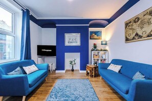 This city centre living room features a smart TV, comfortable sofas, and a selection of games. The space is modern and inviting, perfect for both relaxation and entertainment.