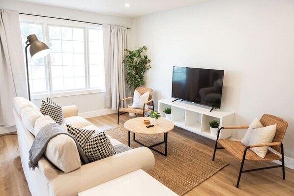 Bright and airy living room with plush seating, a large TV, and tasteful decor, creating the perfect space for relaxation and entertainment.