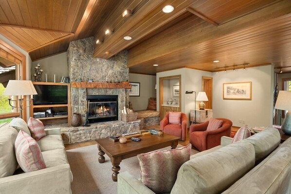 Comfortable living room with woodburning fireplace, ample seating, flat screen TV and views.