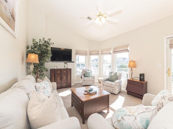 Bright and airy living room with large windows, a smart TV, and comfortable seating, perfect for relaxing with loved ones.