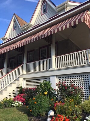 Charming front porch with lush landscaping, perfect for relaxing after a day at the beach.