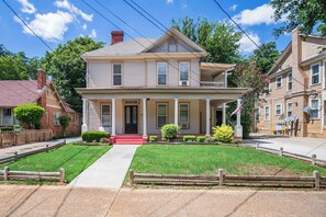The house has light beige siding, a classic gable roof, and prominent white trim, exuding timeless charm. 