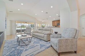 Lake Vista - The living with high vaulted ceilings is equipped with a smart TV, reclining couch and access to the screened in pool area