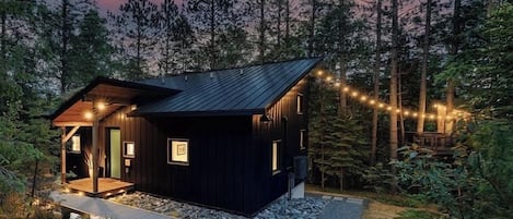 Your cabin and treehouse in the towering pine trees, looking from the parking area.