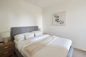 The first bedroom offers a queen-size bed, side tables, reading lamps, and mirrored built-ins.