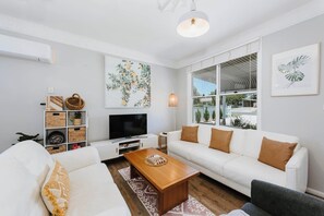 Unwind in the spacious living room, featuring comfortable leather lounges, reverse cycle air conditioning and stylish decor.