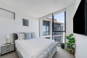 The primary bedroom has a queen-size bed, TV, walk-in robes and a pristine ensuite, with air conditioning in both bedrooms.