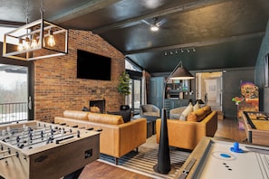 Stylish game room with arcade games, shuffleboard, air hockey, foosball, 75" TV.