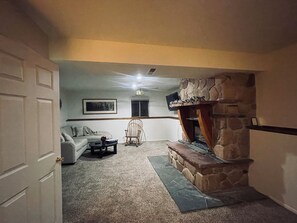 Downstairs family room with a big TV on the wall. 
Fireplace, but is not working