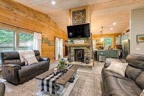 Cozy Living Room with sofa, loveseat, recliner, double-sided woodturning fireplace and smart TV.