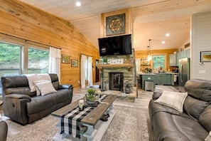Cozy Living Room with sofa, loveseat, recliner, double-sided woodturning fireplace and smart TV.