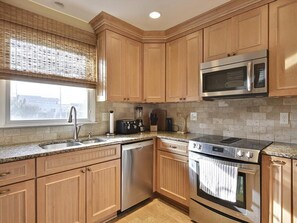 Full kitchen featuring granite countertops, custom cabinetry, stainless steel appliances, and a peninsula for casual dining.