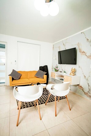 Relax in this bright and stylish living room featuring a cozy sofa, chic décor, a smart TV for entertainment, and ample natural light. Perfect for unwinding after a day of exploring Aruba.
