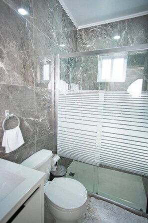 Elegant full bathroom with sleek finishes, a modern walk-in shower, and all the essentials for a refreshing start to your day.