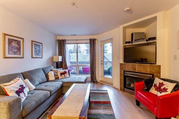 Cozy living room with a sectional sofa, vibrant accent pillows, and a wood-burning fireplace, creating the perfect atmosphere for relaxation.