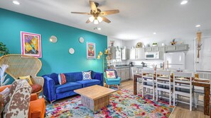 Bright, colorful downstairs living area with cozy seating, vibrant decor, & a fully equipped kitchen