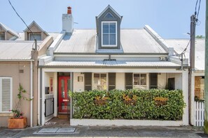 A classic Paddington terrace with a welcoming red door and leafy frontage.