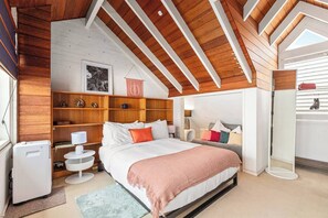 The charming loft-style primary bedroom with vaulted timber ceilings and warm, inviting decor. It offers portable heating and cooling, and an open ensuite.