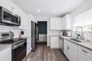 Cook and gather in the spacious kitchen, equipped with a stove, oven, and ample counter space on one side, and a convenient sink on the other, perfect for meal prep and entertaining.