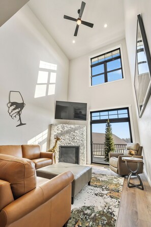 Vaulted, bright living room with gas fireplace, Smart TV and access to a deck