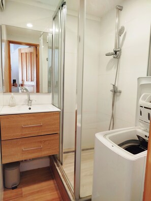 Salle de bain avec meuble vasque et miroir, grande douche et lave-linge