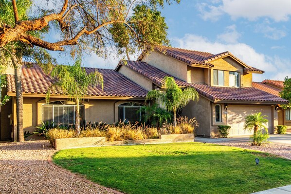 Front lawn and garden view at golden hour, capturing the warm desert sunlight.