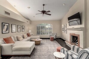 Cozy living room with plush sectional, warm tones & fireplace under Smart TV.