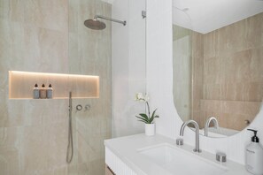 Stylish main bathroom featuring a relaxing bathtub, spacious shower, and a sleek sink with a large mirror, creating a perfect blend of functionality and design.