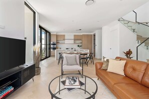 Relax and unwind in this inviting lounge area, complete with a TV, coffee table, and board games – just steps away from the kitchen for effortless entertaining.