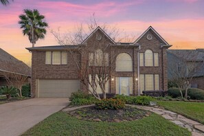 Stunning two-story brick home with a spacious driveway, and a beautifully landscaped front yard.