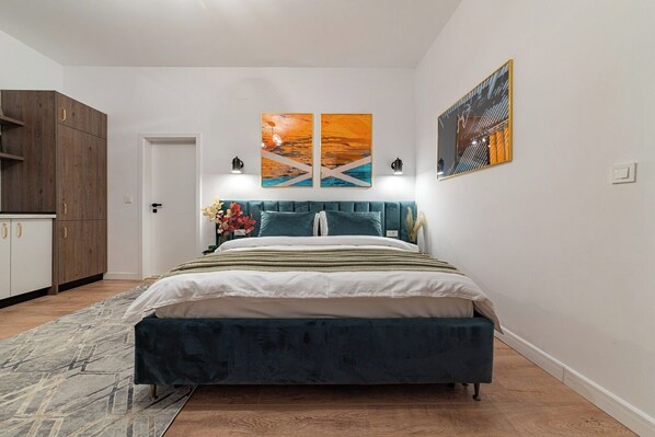 Modern studio equipped with king size bed dressed in cotton linens, soft pillows, bedside tables, stylish carpet on the floor, clothes storage, heating, AC