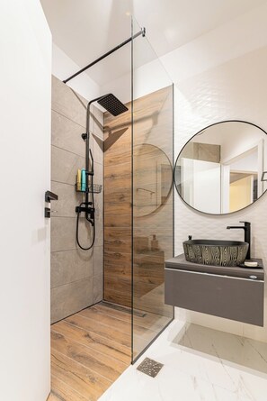Modern bathroom with walk-in shower, sink, toilet, mirror and complimentary toiletries
