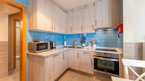 A fully equipped kitchenette featuring sleek appliances, a vibrant blue backsplash, and ample cabinet space for your culinary needs. #ModernKitchen #VacationRental
