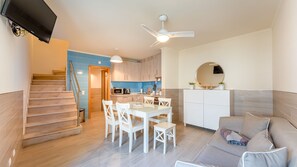 Enjoy the open-plan design with comfortable seating, a dining area, and easy access to the kitchenette. Perfect for relaxing after a day at the beach. #CozyLiving #BeachEscape