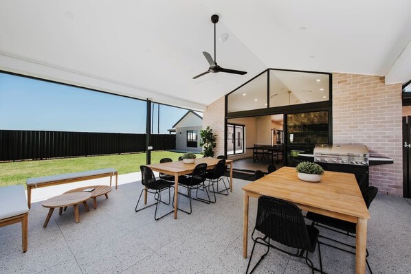The property boasts beautiful alfresco dining space, with multiple seating areas flanked by the grassy yard.